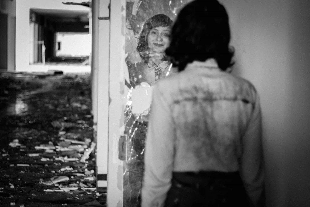 woman staring into broken mirror