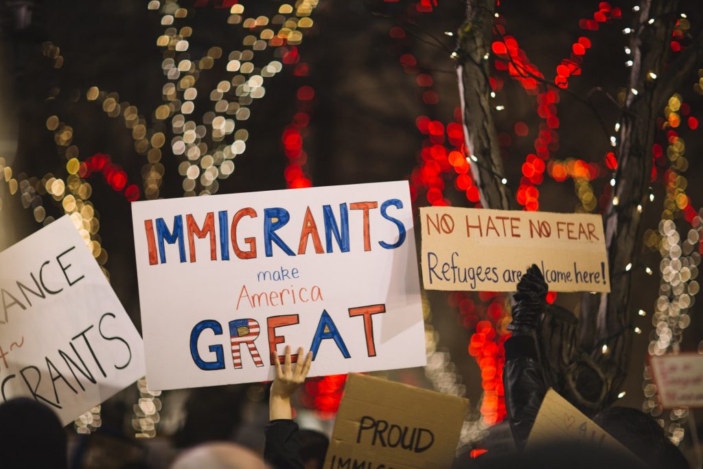 woman holds a sign that says "Immigrants are great"